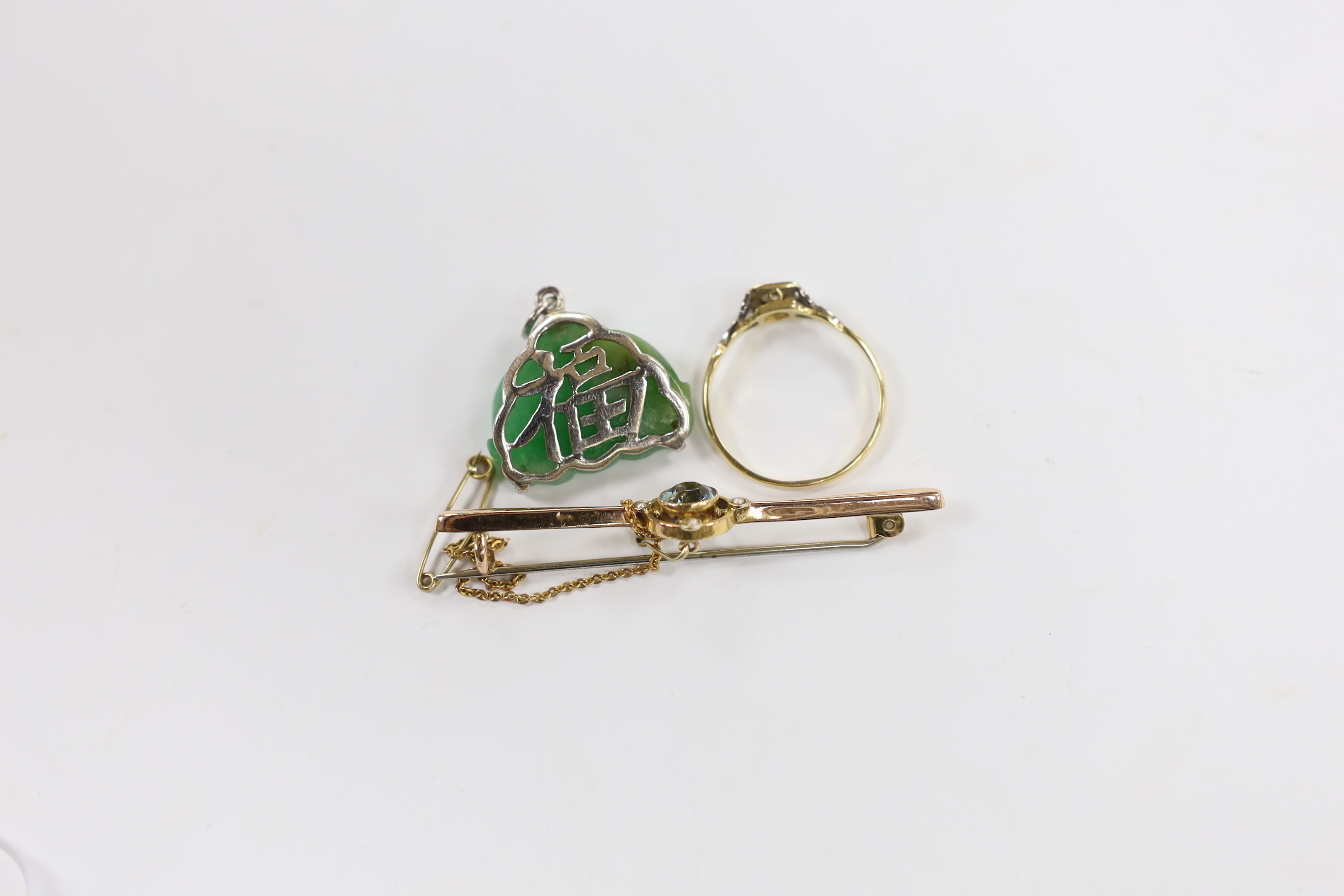 An Edwardian 9ct, aquamarine and seed pearl cluster set bar brooch, 54mm, a Chinese mounted jade Buddha pendant and an 18ct and single stone diamond set ring, with diamond chip set shoulders.
